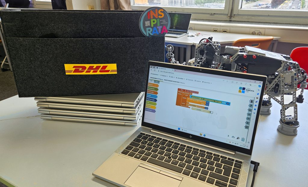 Laptop auf einem Tisch neben einer Tasche mit DHL-Logo