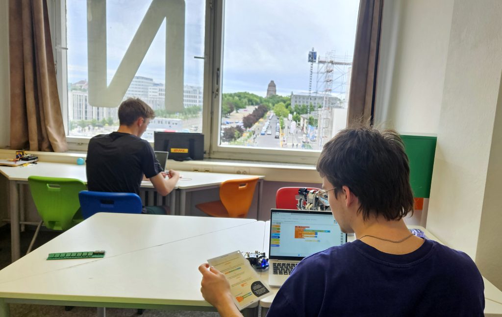 Zwei Personen an Tischen mit Laptops.